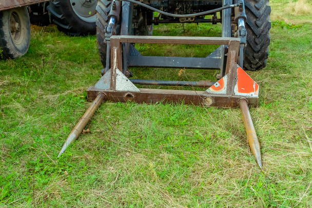 Traktor s mechanickými upevňovacími prvky ležícími na zemi. - Fotografie, Obrázek