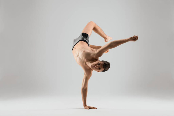 Flexible man dancing breakdance on one hand - Photo, image