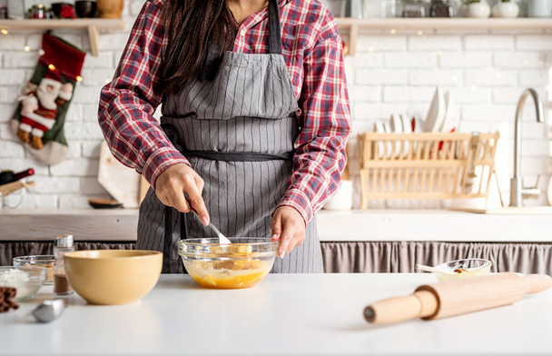 Kochen und Backen. Junge lateinamerikanische Frau schlägt Eier in der Küche - Foto, Bild