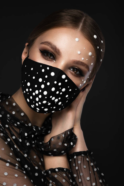 Portrait of a beautiful woman in a black mask with pearls and classic makeup. Mask mode during the covid pandemic - Foto, Imagem
