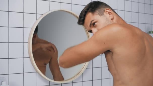 displeased man smelling armpits and grimacing in bathroom - Footage, Video