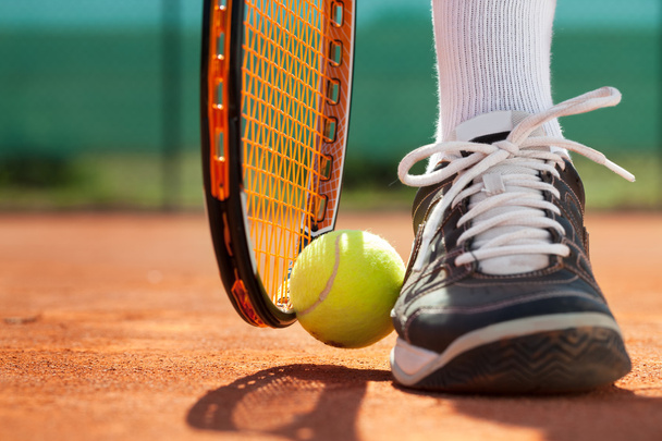 Legs of athlete near the tennis racket and ball - Foto, imagen