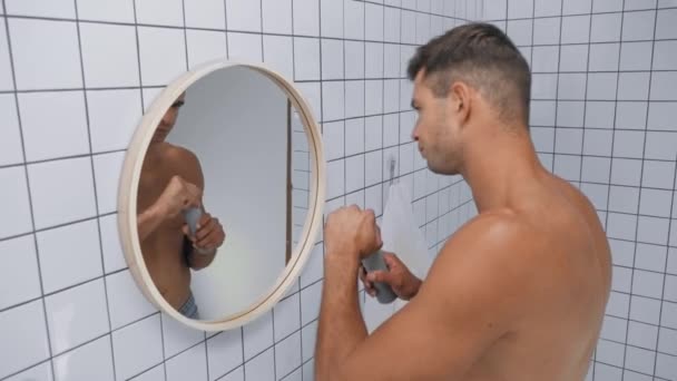 Üstsüz adam banyoda aynanın yanına deodorant sürüyor. - Video, Çekim