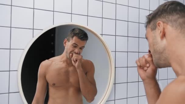 Schläfriger Mann gähnt, berührt Gesicht und puffende Wangen beim Blick in den Spiegel - Filmmaterial, Video
