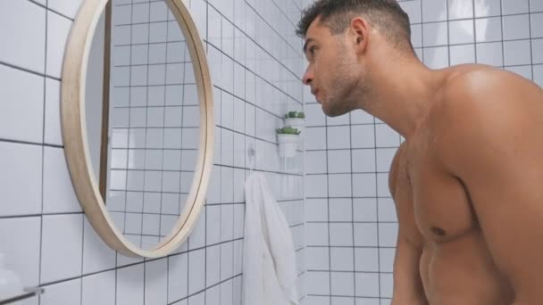 Hemdloser Mann mit Blick auf Spiegel und Waschgesicht  - Filmmaterial, Video