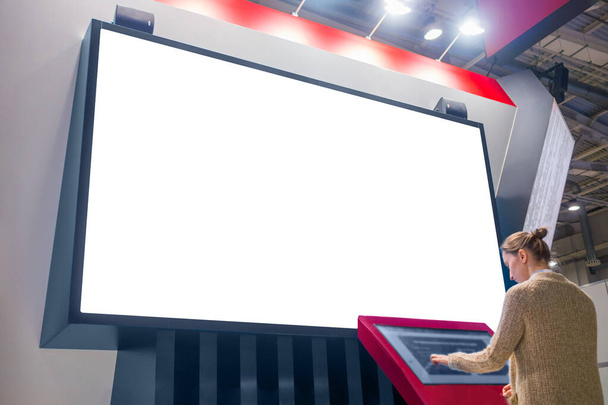 Mockup εικόνα - γυναίκα κοιτάζοντας λευκό κενό μεγάλη οθόνη τοίχου - Φωτογραφία, εικόνα