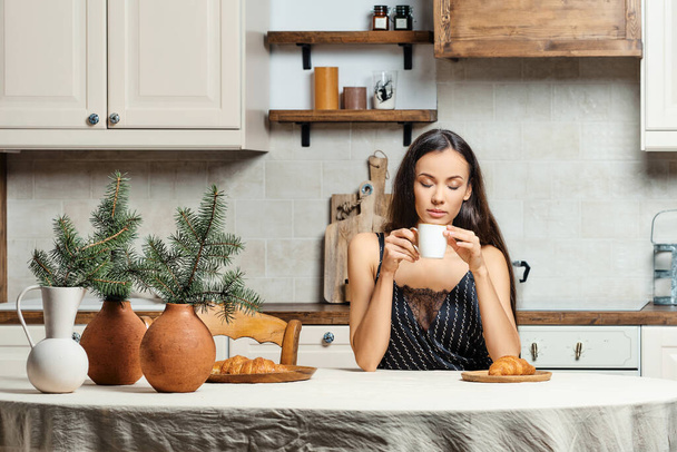 Sleepy mixed race woman drinking fresh coffe in the kitchen in the morning - Foto, Imagen