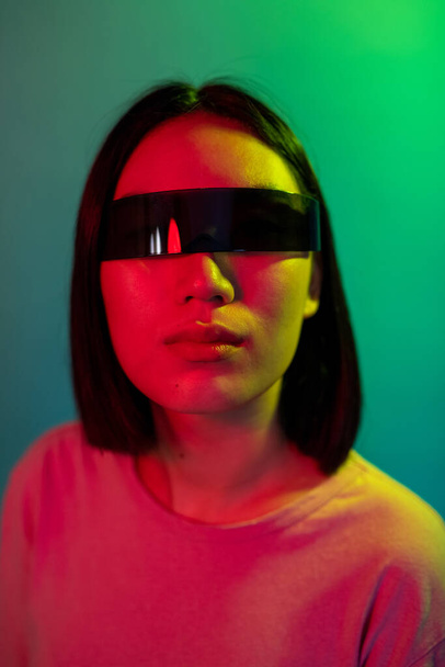 Mladá asijská žena nosí chytré brýle na barevném pozadí těší rozšířenou realitu - Fotografie, Obrázek