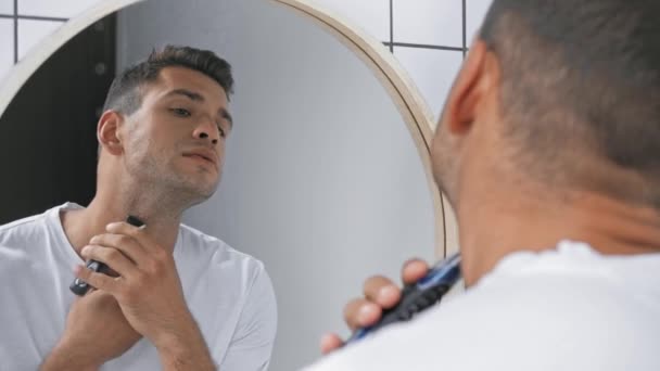 férfi a póló borotválkozás arc, miközben nézi a tükör - Felvétel, videó