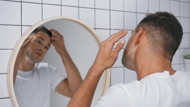 jeune homme brossant les cheveux tout en regardant miroir dans la salle de bain - Séquence, vidéo