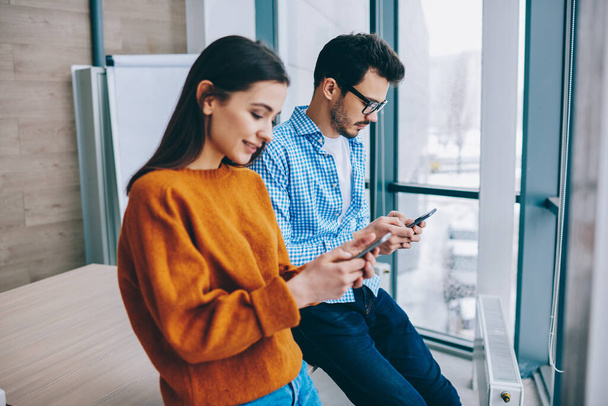 Caucasian millennials using modern cellphones for sharing media files via bluetooth connection, male and female prefer mobile communication ignoring live talking for doing social networking - Photo, image