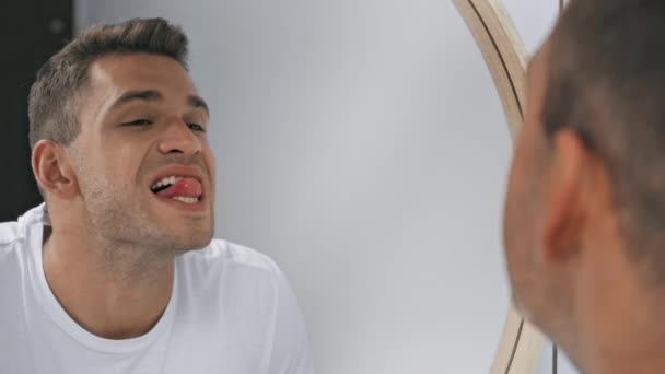 Χαρούμενος άντρας που κοιτάζει λευκά και καθαρά δόντια στον καθρέφτη  - Πλάνα, βίντεο