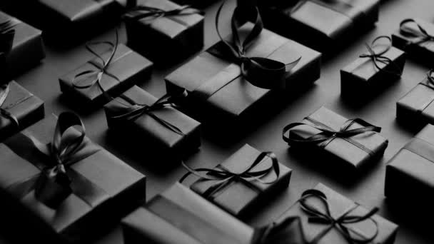 Elegancki czarny motyw świąteczny. Zapakowane prezenty w czarny matowy papier ze wstążką - Materiał filmowy, wideo