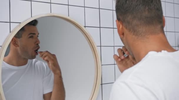 rack focus van de mens kijken naar spiegel terwijl het poetsen van tanden  - Video