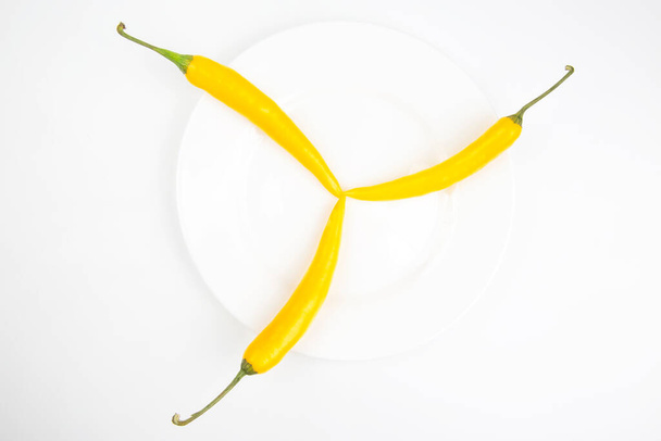 trzy żółte ostre papryki chili na białym poszyciu - Zdjęcie, obraz