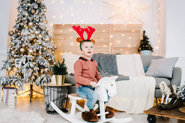 Boy playing near Christmas tree. Happy New Year and Merry Christmas. Christmas decorated interior. The concept of family holiday. - Foto, Imagen