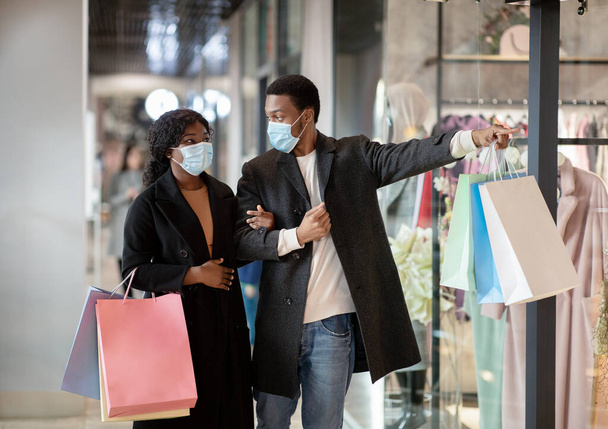 Ritratto di coppia in maschere protettive shopping in centro commerciale durante coronavirus pandemia e distanza sociale - Foto, immagini