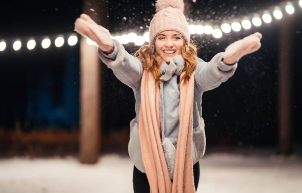 Beautiful young woman Playing with snow evening in the winter park. Happy  woman having fun on winter holidays. Christmas, New year. Winter lifestyle. - Фото, изображение