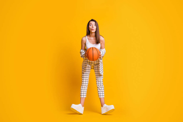 Photo of adorable attractive young woman hold game ball excited look ready play basketball wear singlet pants sneakers isolated bright yellow color background - Fotoğraf, Görsel