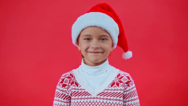 hymyilevä tyttö santa hattu ja joulu pusero eristetty punainen - Materiaali, video