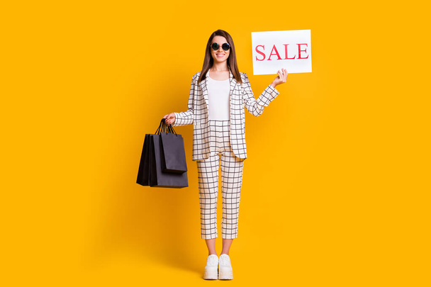 Full length body size photo of cheerful girl keeping black friday sale sign packages wearing sunglass isolated on bright color background - Фото, изображение