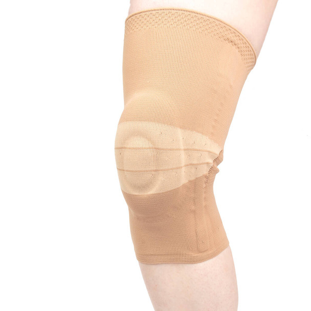 verband voor het bevestigen van de gewonde knie van het menselijk been op een witte achtergrond. geneeskunde en sport. ledematen letsels behandelaars - Foto, afbeelding