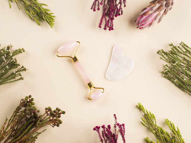 Rolo de rosto de guasha de quartzo no fundo floral - Foto, Imagem