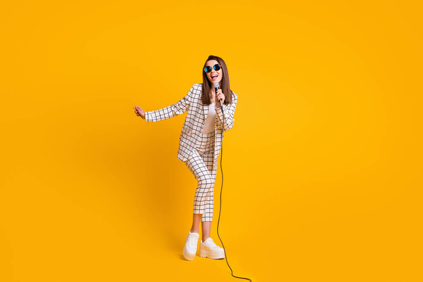 Full length body size photo of girl performing with microphone on festival stage wearing sunglass isolated on bright yellow color background - Foto, Bild