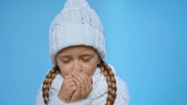 girl in knitted white winter outfit coughing isolated on blue - Video, Çekim