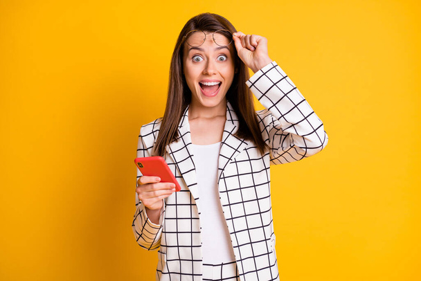 Photo portrait of shocked amazed female freelancer using device staring with opened mouth isolated on vivid yellow color background - Foto, imagen