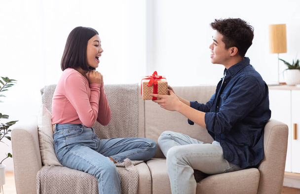 Korean Boyfriend Giving Gift Box Girlfriend Celebrating Holiday At Home - 写真・画像