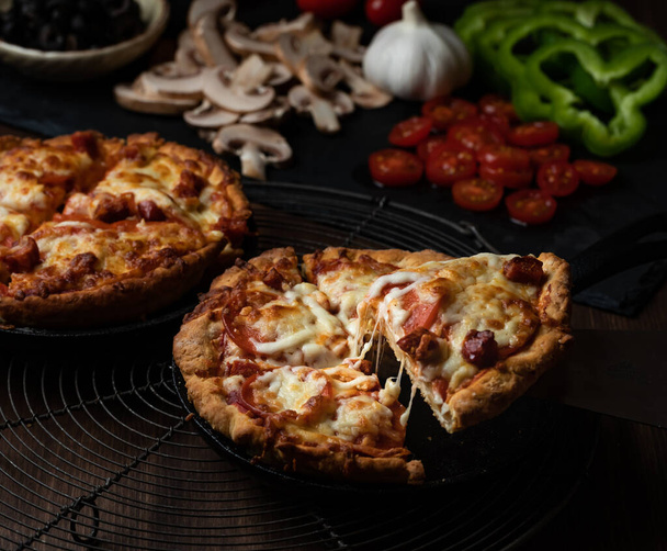 Close-up zicht op twee diepe schotel pizza 's met een plak wordt genomen uit een. - Foto, afbeelding
