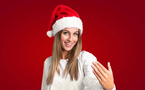 Girl with christmas hat over isolated background inviting to come - Photo, Image