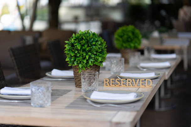 A placa é reservada na mesa servida de um café ou restaurante ao ar livre de verão. Profundidade rasa do campo, fundo embaçado - Foto, Imagem