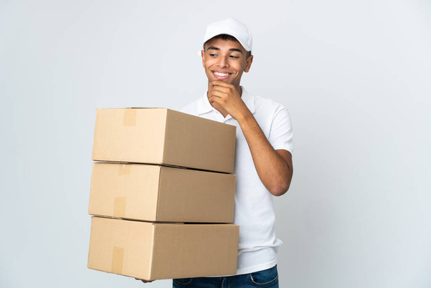 Delivery Brazilian man isolated on white background looking to the side and smiling - Foto, Imagem