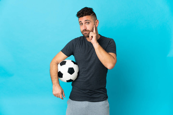 Football player isolated on blue background thinking an idea - Foto, afbeelding