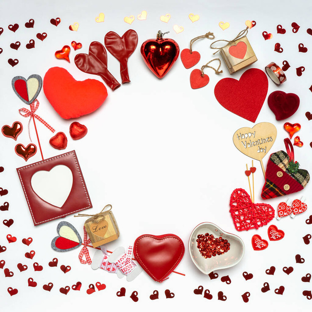 Round frame made of various decorative red hearts and romantic items: gifts, sweets, photoframe on white background. Love, romance or Valentine's day concept. Greeting card with space for text. - Foto, Bild