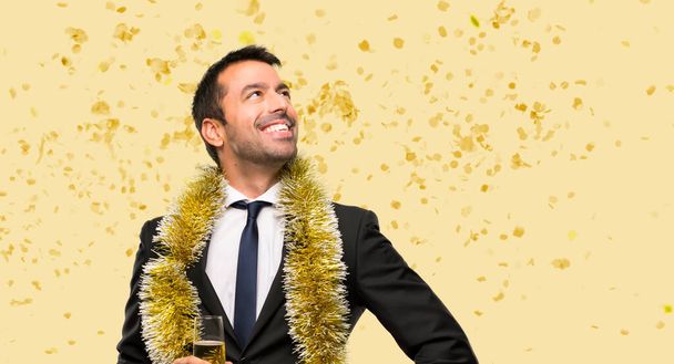 Mann mit Champagner feiert Neujahr mit Armen an der Hüfte und lachend mit Konfetti auf einer Party - Foto, Bild