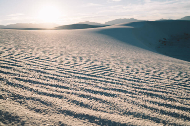 Picturesque view of rough sandy dunes in desert in White Sands National Park against cloudy blue sky and bright sun - Foto, afbeelding