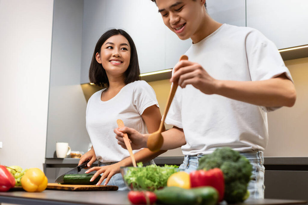 feliz casado asiático pareja cocina ensalada juntos de pie en cocina - Foto, imagen