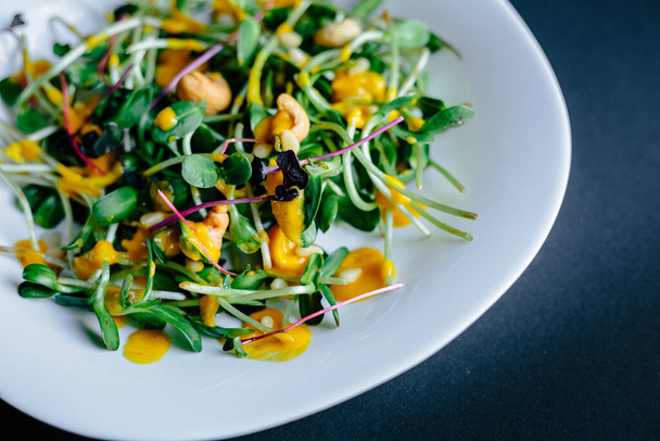Ассортимент свежей микрозелени закрывает салат на белой тарелке. Здоровый салат со шпинатом, киноа и жареными овощами - Фото, изображение