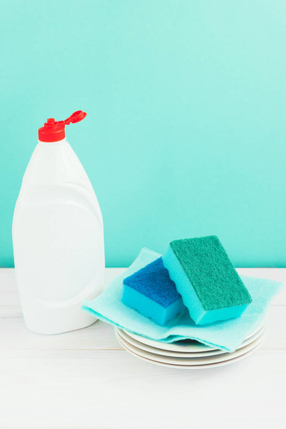 Bottle of dish washing, sponges, utensils on white wooden table against a green wall background - Foto, immagini