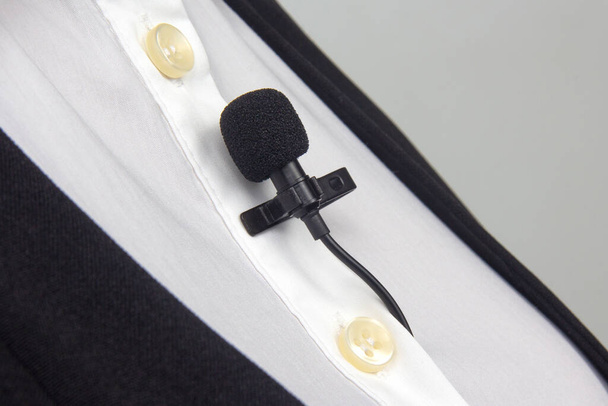 クリップ・オン・ラバリエのマイクは女性の服のクローズアップに取り付けられています。コンデンサーマイクで声の音を録音する - 写真・画像