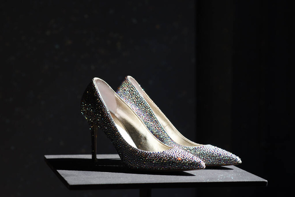 Egy pár elegáns magassarkú udvari cipő csillogó strasszokkal díszítve, sötét háttérrel és egy különleges alkalomra vagy esküvőre kész copyspace-sel. - Fotó, kép