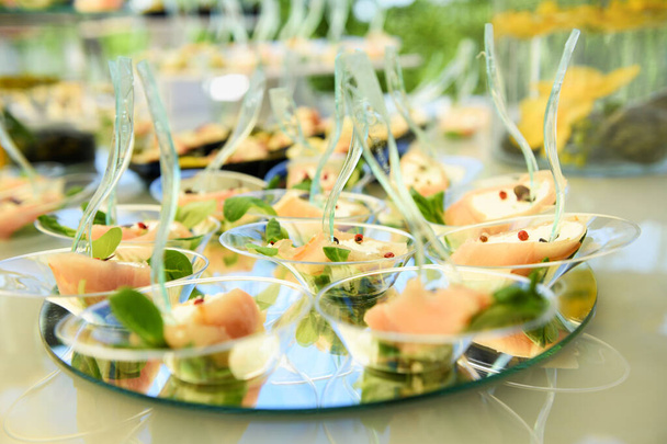 Stół bufetowy z ekspozycją przystawek z owoców morza łososia na okrągłych lusterkach o niskim kącie płytkiego widoku podczas imprezy gastronomicznej lub wesela - Zdjęcie, obraz