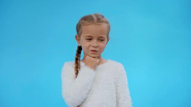 pensive girl in fluffy sweater showing idea gesture and smiling isolated on blue - Felvétel, videó