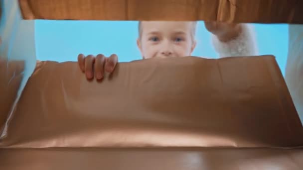 überrascht Mädchen im flauschigen Pullover Öffnung Box isoliert auf blau - Filmmaterial, Video