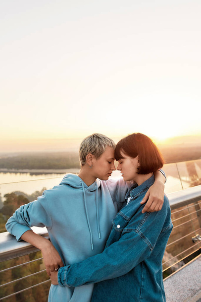 Young lesbian couple cuddling outdoors, Two women enjoying romantic moments together at sunrise - Фото, изображение