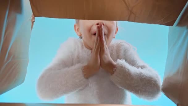 chica en suéter esponjoso apertura caja con las manos de oración aislado en azul - Metraje, vídeo