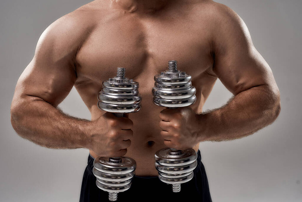 Young muscular caucasian male athlete lifting dumbbells - Foto, Imagem